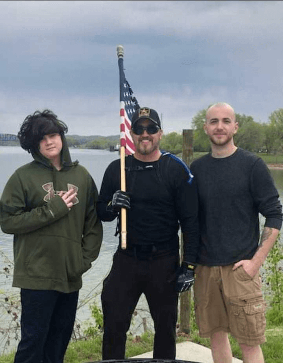 Founder Max Maxfield holding an American Flag while standing between his sons